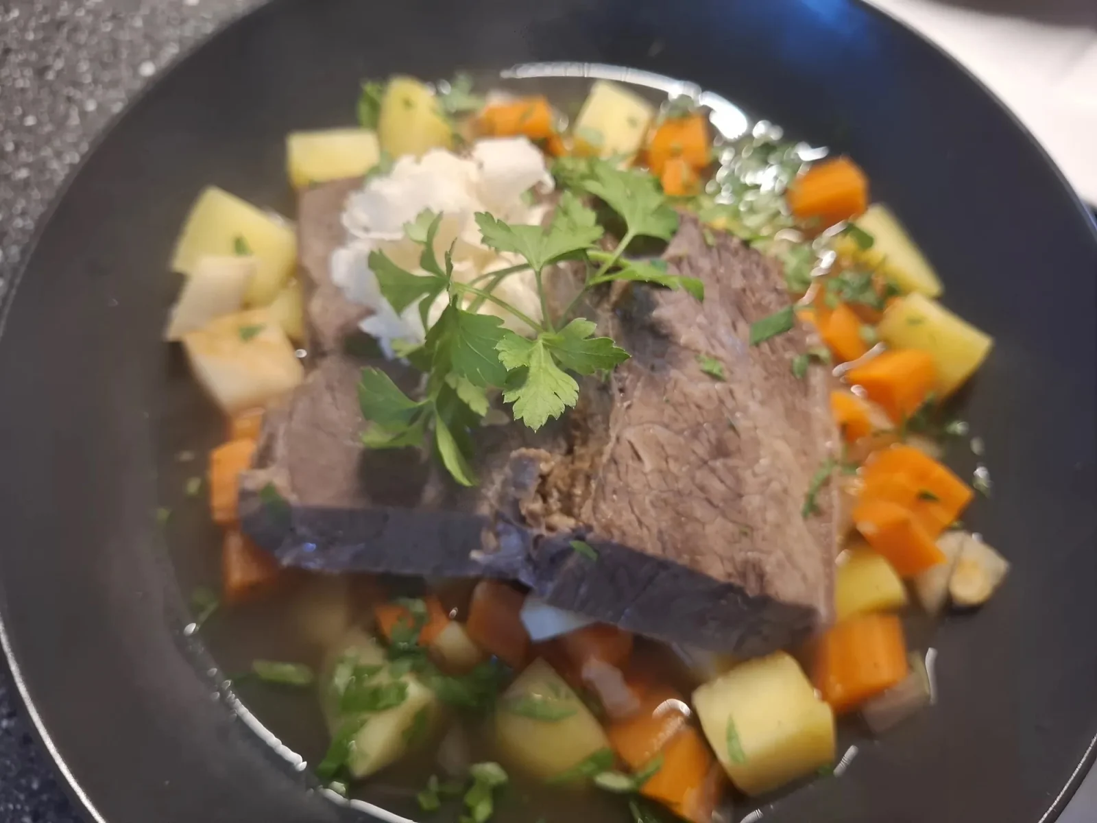 Gekochtes Rindfleisch mit Wurzelgemüse in klarer Brühe