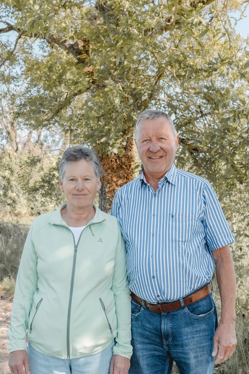Die Eltern der Familie Unkelbach zwischen Obstbäumen auf dem Hofgelände